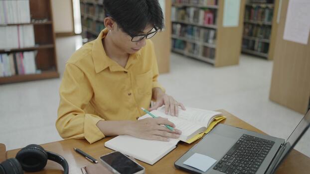 Student reviewing handwritten notes and a laptop in a library